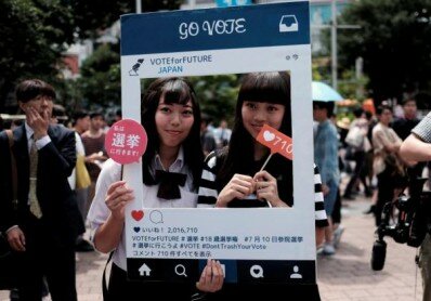 High school students pose for photos with a cardboard Instagram frame calling on youths to vote in the July 10 upper house election, in Tokyo